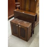 A SMALL MAHOGANY DROP LEAF OCCASIONAL TABLE, ON END STANDARDS AND A MAHOGANY MURAL SMALL CUPBOARD (