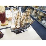 A SMALL MODEL OF A THREE MASTED SAILING SHIP UNDER SAIL, ON STAND