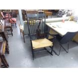A STYLISH ART DECO EBONISED ROCKING CHAIR WITH STICK BACK AND RUSH SEAT