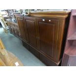 A LARGE MAHOGANY THREE DOOR TELEVISION AND STEREO CABINET, RAISED ON BUN FEET
