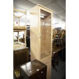 A TALL, NARROW LIGHT OAK DISPLAY CABINET WITH DRAWER AND CUPBOARD BELOW, 20" WIDE