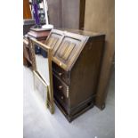 A CARVED OAK BUREAU WITH LINEN FOLD PANELS, THREE DRAWERS BELOW