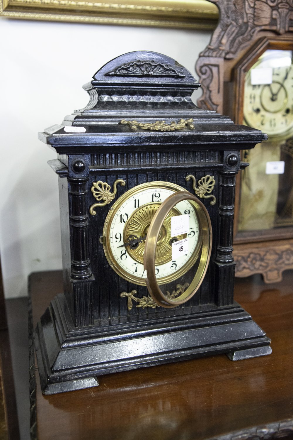 AN EIGHT DAY MANTEL CLOCK, STRIKING ON A GONG, WITH BRASS DECORATIONS ON EBONISED CASE