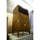 A WALNUTWOOD BEDSIDE CUPBOARD WITH CONCAVE FRONT