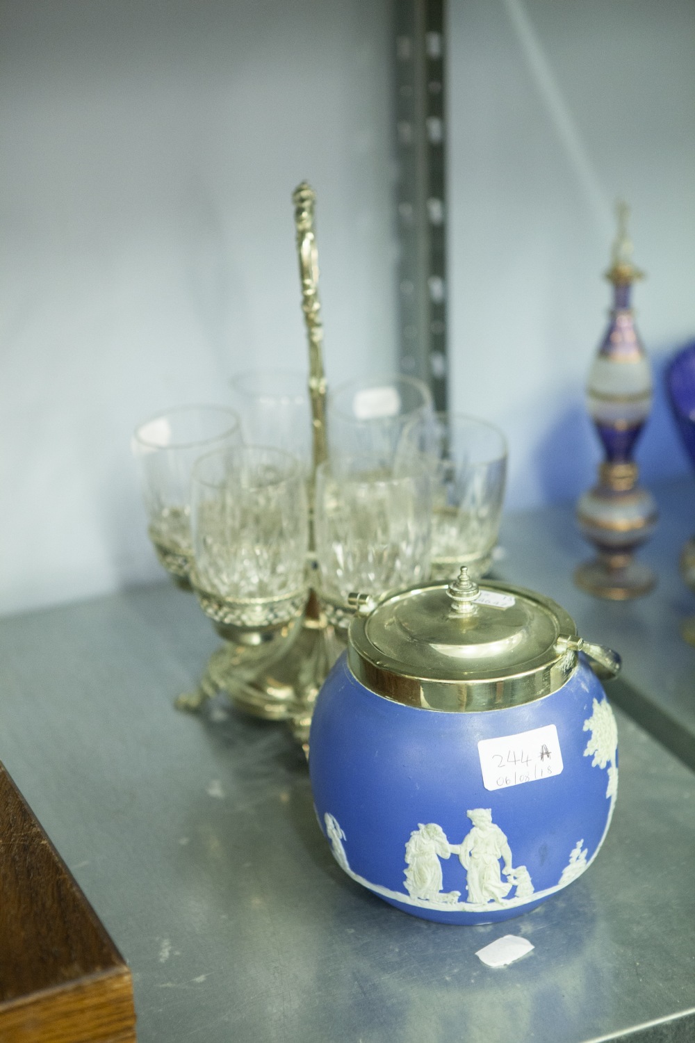 A SILVER PLATE DRINKING GLASS HOLDER, THE SIX CUT GLASSES, RAISED ON PIERCED TRAYS WITH OVERHEAD