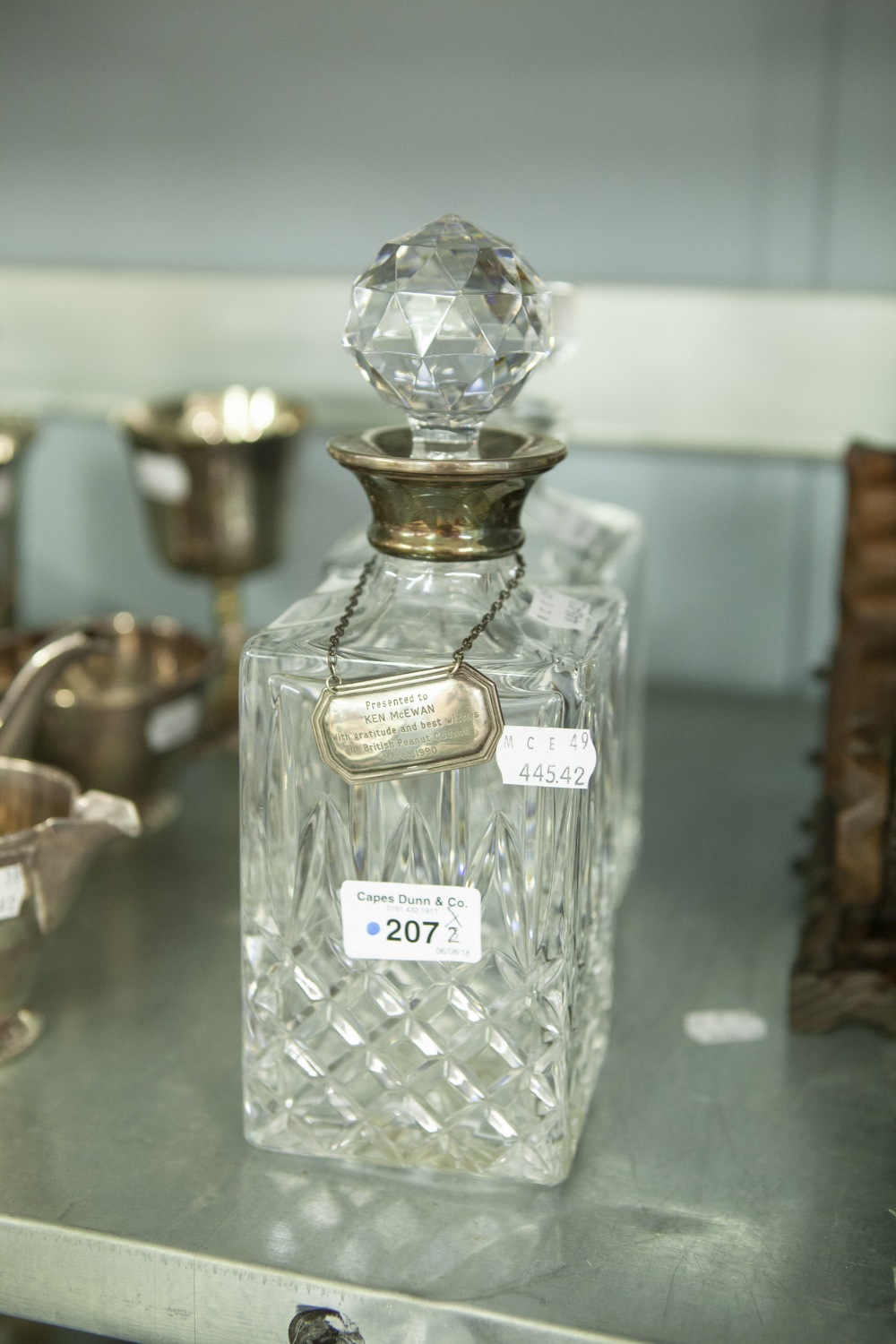 A DECANTER WITH SILVER COLLAR AND SILVER NAME PLATE, ENGRAVED 'PRESENTED TO KEN McEWAN' AND