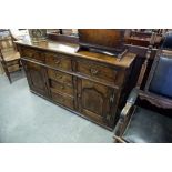 AN EDWARDIAN OAK SIDEBOARD WITH FOUR CENTRAL GRADUATED DRAWERS, FLANKED BY A DRAWER AND CUPBOARD