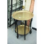 AN EARLY 20th CENTURY ORIENTAL TWO TIER BRASS AND JAPANNED WOODEN FOLDING STAND