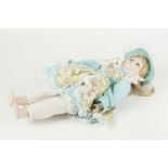 PORCELAIN HEAD DOLL, with fixed blue eyes, blonde hair, and soft body, in blue and floral dress with
