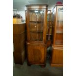 A MODERN REPRODUCTION MAHOGANY SHALLOW BOW-FRONT STANDING CORNER CUPBOARD WITH GLAZED UPPER PORTION,