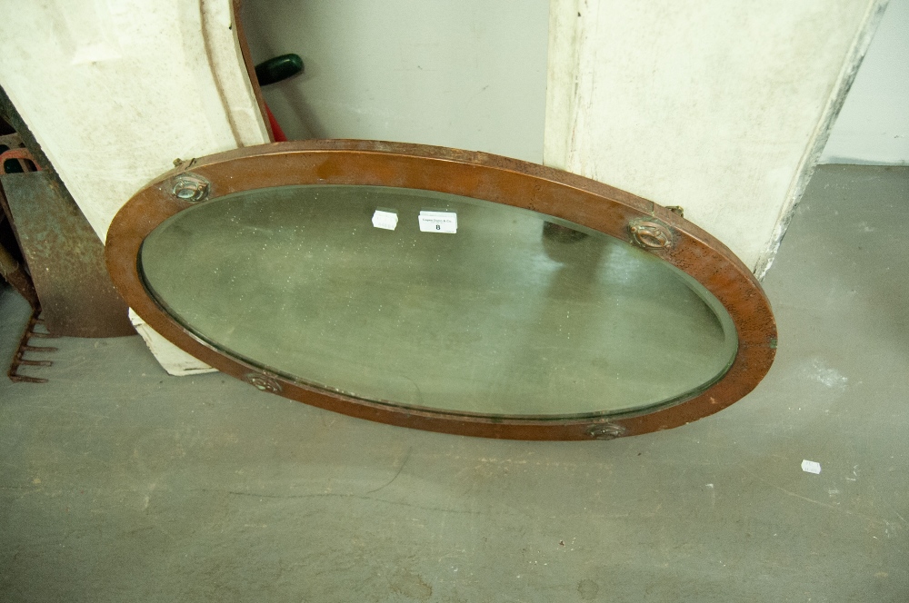 A HAMMERED COPPER OVAL WALL MIRROR