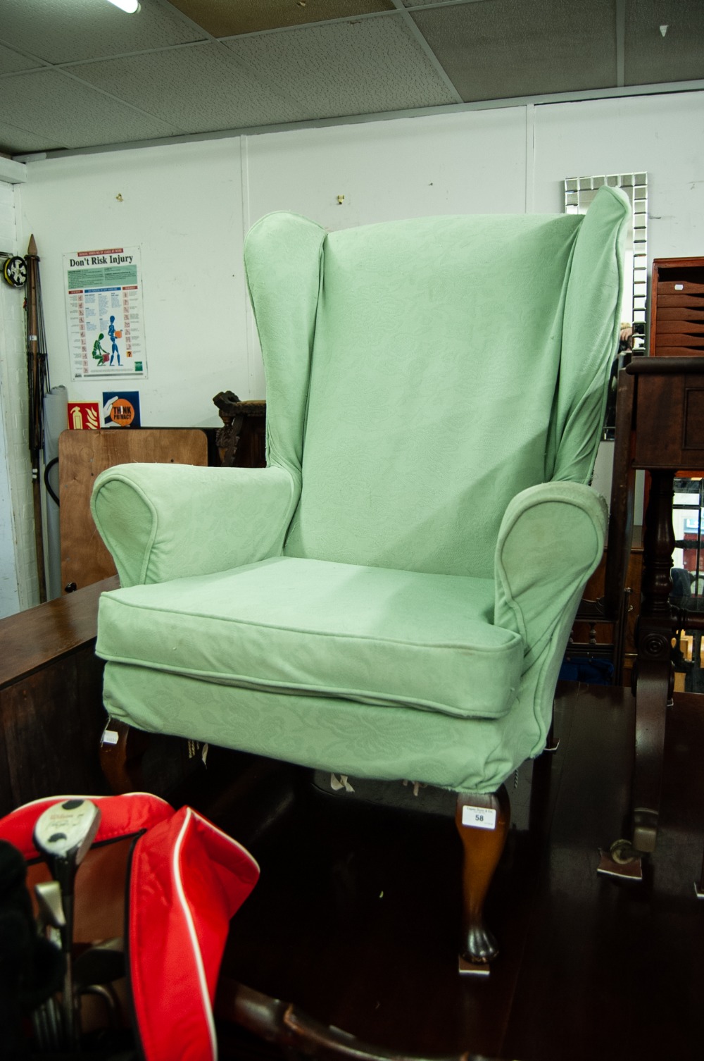 A FIRESIDE ARMCHAIR, RAISED ON CABRIOLE SUPPORTS