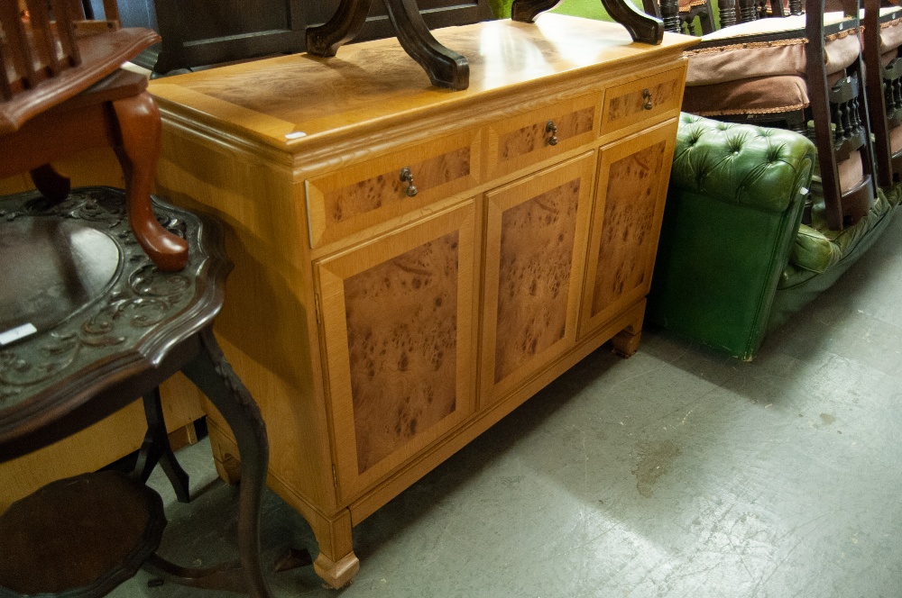 A REVOLVING BOOKCASE AND A MODERN LIGHT WOOD SIDEBOARD, HAVING THREE CENTRAL DRAWERS AND CUPBOARDS