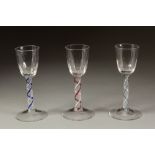 THREE NEAR MATCHING EIGHTEENTH CENTURY COLOUR TWIST WINE GLASSES, each with hammered ogee bowl and