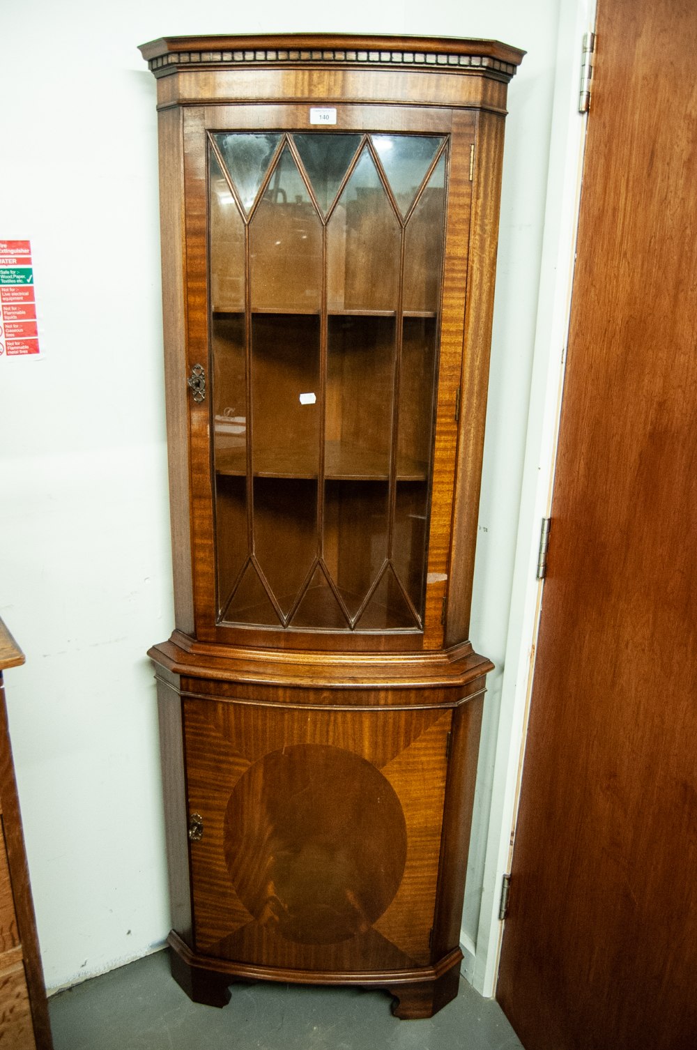 A MODERN REPRODUCTION MAHOGANY SHALLOW BOW-FRONT STANDING CORNER CUPBOARD WITH GLAZED UPPER PORTION,