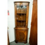 A MODERN REPRODUCTION MAHOGANY SHALLOW BOW-FRONT STANDING CORNER CUPBOARD WITH GLAZED UPPER PORTION,