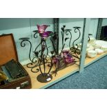 PAIR OF BLACK WROUGHT IRON PLANT FORM THREE LIGHT CANDELABRA WITH PURPLE GLASS SCONCES AND THE