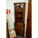 A MODERN REPRODUCTION MAHOGANY SHALLOW BOW-FRONT STANDING CORNER CUPBOARD WITH GLAZED UPPER PORTION,