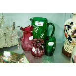 A GREEN GLASS JUG AND CUP WITH LILY OF THE VALLEY PAINTED DECORATION, CRANBERRY GLASS JUG AND TWO