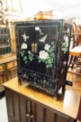 A MODERN BLACK LACQUER CHINESE PETIT CABINET, TWO DOORS OVER TWO SHORT DRAWERS, DECORATED WITH LOW