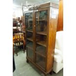 A CARVED OAK BOOKCASE ENCLOSED BY TWO GLAZED DOORS WITH FOUR ADJUSTABLE SHELVES ON TURNIP FEET, 3'