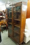 A CARVED OAK BOOKCASE ENCLOSED BY TWO GLAZED DOORS WITH FOUR ADJUSTABLE SHELVES ON TURNIP FEET, 3'