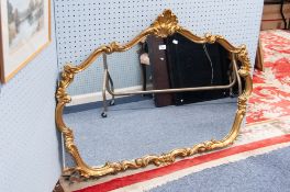 A LARGE GILT FRAMED WALL MIRROR, SHAPED GLASS WITH SCROLL FRAME
