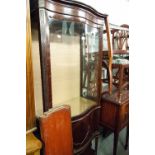 REGENCY MAHOGANY SERPENTINE DISPLAY CABINET ON BASE HAVING SINGLE CUPBOARD, OVER UNDERTIER ON SQUARE