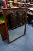 AN EARLY/MID 20th CENTURY MAHOGANY FRAMED WALL MIRROR, CARVED TOP RAIL OVER SHAPED MIRROR