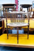 EDWARDIAN MAHOGANY ARMCHAIR WITH CARVED BACK RAIL AND SCROLL ARMS, SPINDLE BACK OVER PAD SEAT, ON