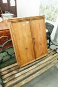 A PINE TWO DOOR WALL CUPBOARD