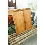 A PINE TWO DOOR WALL CUPBOARD