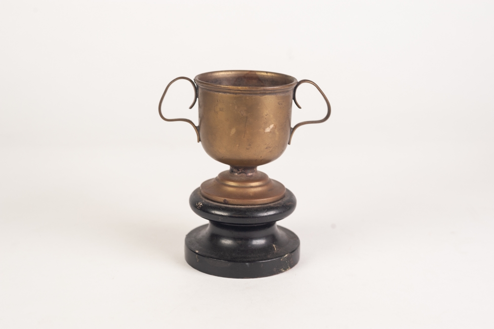 A WHITE STAR LINES R.M.S. MAJESTIC BRASS TWO HANDLED TROPHY CUP, on wooden stand, 4 1/2" (11.5cm) - Image 2 of 2