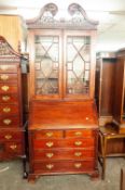 A REPRODUCTION MAHOGANY BUREAU BOOKCASE, THE TOP WITH ASTRAGAL GLAZED DOORS ENCLOSING TWO WOODEN