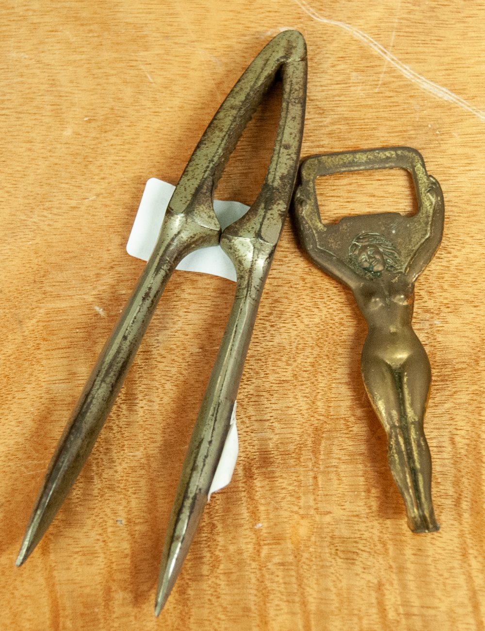 A BRASS BOTTLE OPENER IN THE FORM OF A NUDE LADY AND A WHITE METAL NUTCRACKER (2)