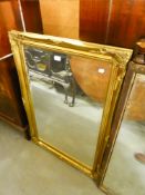 A MODERN OBLONG BEVELLED EDGE WALL MIRROR IN GILT FRAME