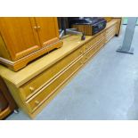 A LARGE LOW LIGHTWOOD LOUNGE UNIT OF FOUR LONG DRAWERS AND A MATCHING TWO DRAWER UNIT
