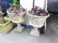 A PAIR OF COMPOSITION GARDEN URNS WITH HEAD DECORATION TO THE SHALLOW BOWLS, ON SWEPT PEDESTALS (2)