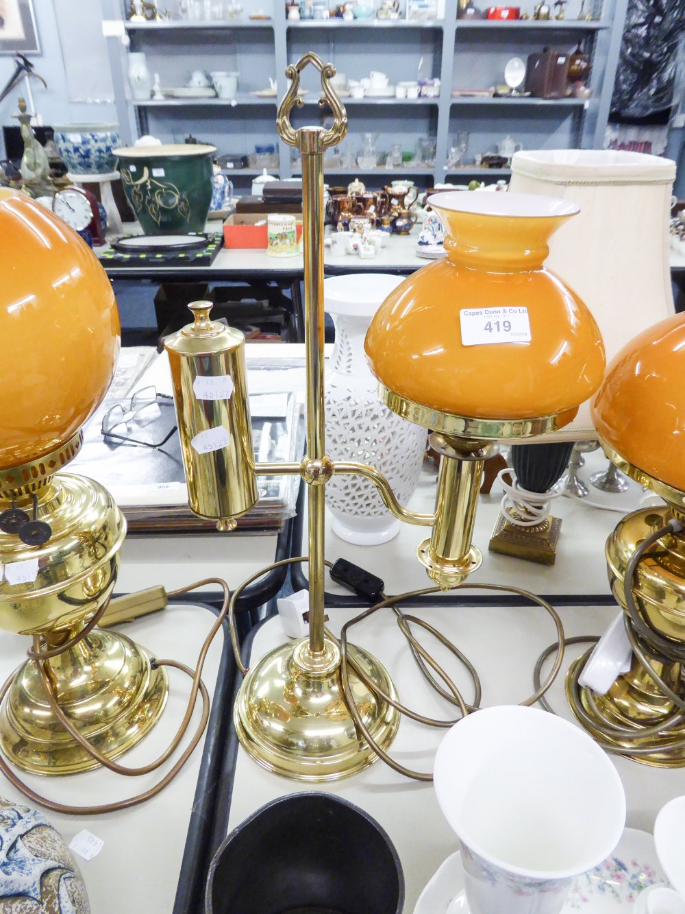 AN ADAPTED OIL LAMP WITH ORANGE GLASS GLOBE AND CLEAR GLASS FUNNEL