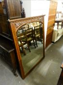 AN EARLY/MID 20th CENTURY MAHOGANY FRAMED WALL MIRROR, CARVED TOP RAIL OVER SHAPED MIRROR