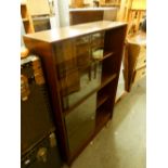 A MID TWENTIETH CENTURY GLAZED BOOKCASE WITH SLIDE DOORS, ENCLOSING THREE SHELVES