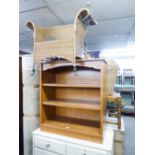 A MODERN BOOKCASE HAVING TWO SHELVES, WICKER ARMCHAIR ON WROUGHT IRON SUPPORTS AND A MODERN CREAM