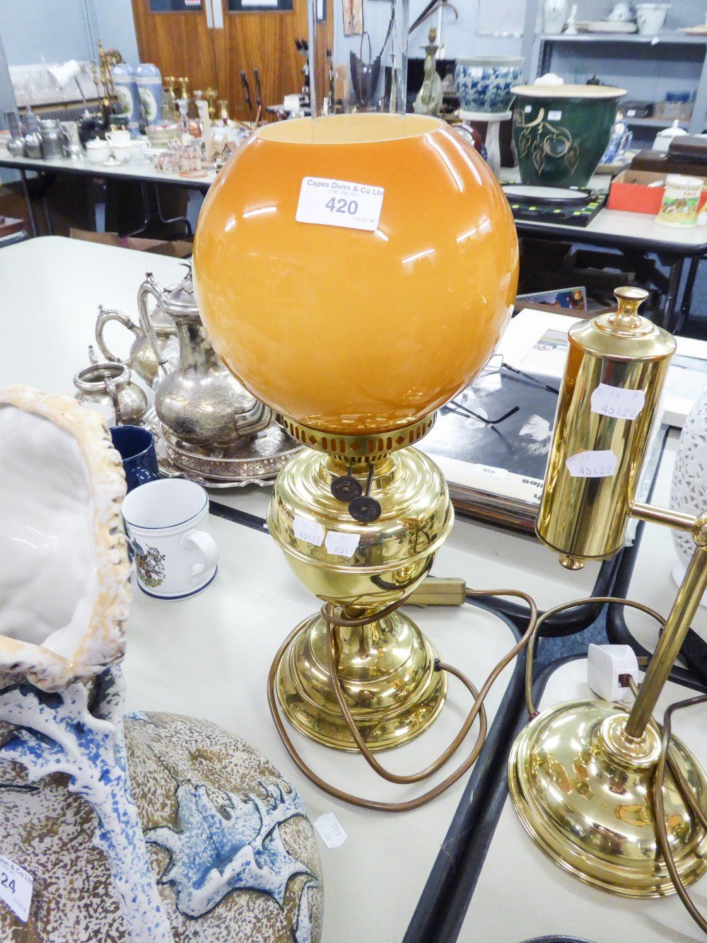 AN ADAPTED OIL LAMP WITH ORANGE GLASS GLOBE AND CLEAR GLASS FUNNEL