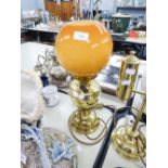 AN ADAPTED OIL LAMP WITH ORANGE GLASS GLOBE AND CLEAR GLASS FUNNEL