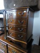 A SMALL FOUR DRAWER SERPENTINE FRONTED CHEST WITH DROP HANDLES