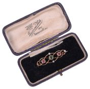 A delicate Edwardian 15ct gold peridot and pink sapphire set scroll brooch,