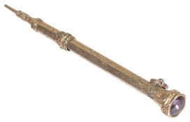 A gilt metal retracting pencil, with hexagonal top inset with amethyst, the body with foliate decora