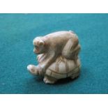 SMALL CARVED IVORY NETSUKE OF A TURTLE WITH MONKEY