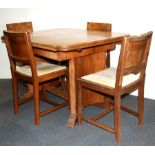 An Art Deco walnut veneered draw leaf table and four chairs.