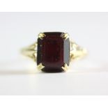 A 9ct yellow gold ring set with an emerald cut garnet, (M).